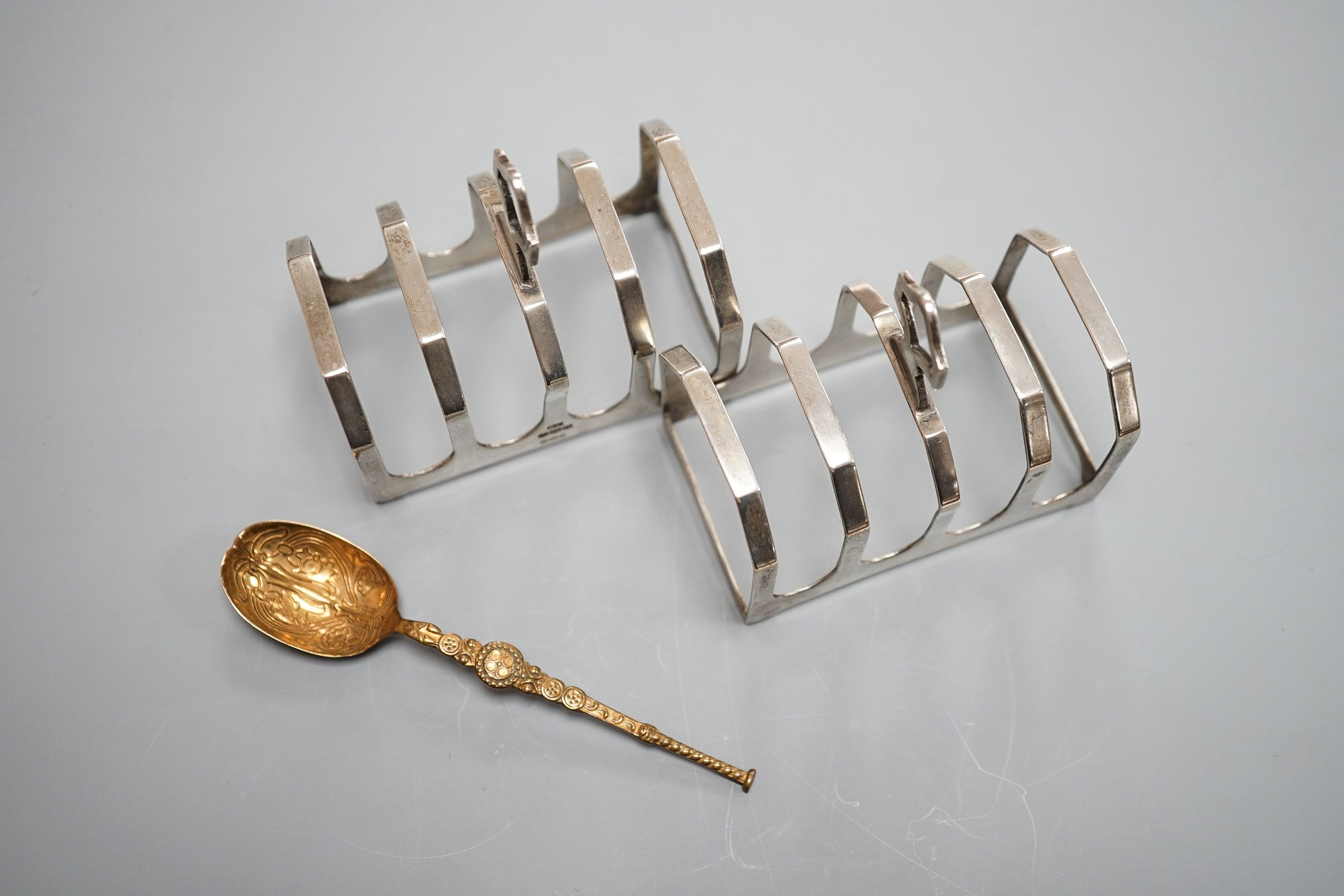 A pair of George VI silver five bar toastracks, Viner's Ltd, Sheffield, 1937, length 76mm and metal replica of a 12th century Coronation spoon.